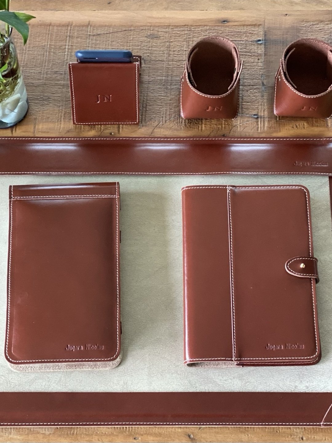 Kit de mesa em couro conhaque sobre bancada de madeira do atelier